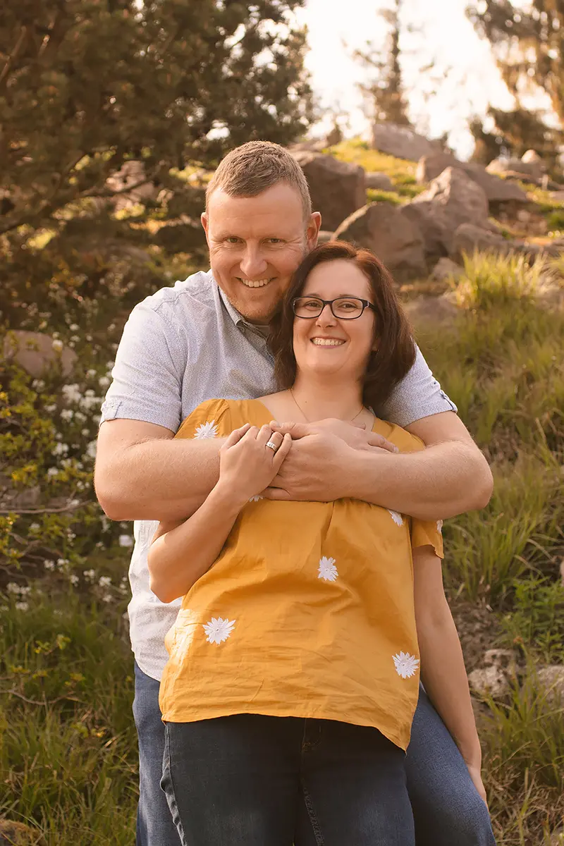 Ein Mann hält seine Frau in den Armen und beide lachen in die Kamera.